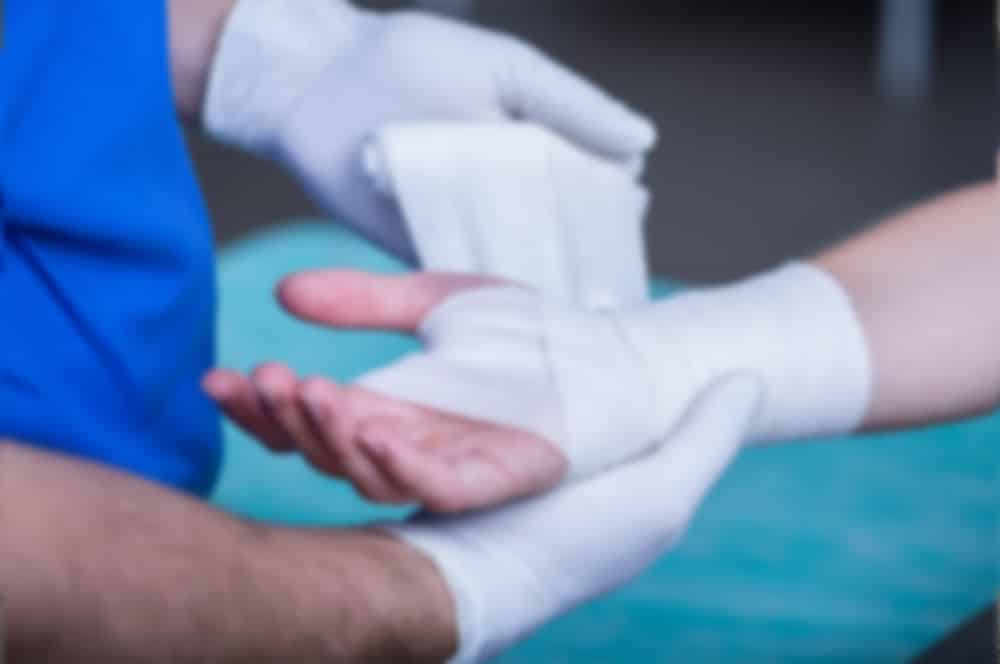 Hand being wrapped in bandages by a nurse