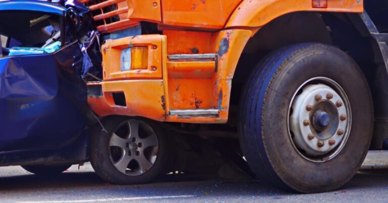 A commercial truck that has crashed into a blue car