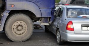 A blue truck that has crashed into a grey car