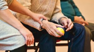 Physical therapist holding the wrist of a patient with a ball in their hand