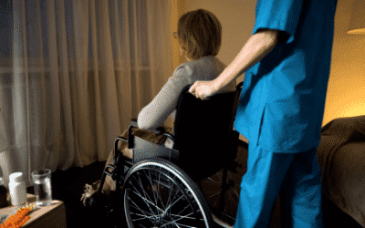 A nurse wearing scrubs pushing an elderly woman in a wheelchair