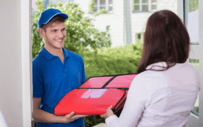 Man in a blue shirt and hat delivering pizza to a woman