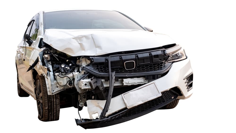 Front and side of a white car damaged in an accident on the road. Damaged car after a collision. Isolated on white background with clipping path.