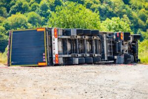 A large cargo truck overturned in a road traffic accident during the day.