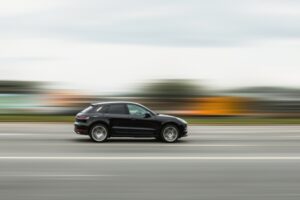 A black car speeds down the street, the background blurred to emphasize its reckless pace. The scene captures the concept of dangerous driving and disobeying traffic rules.