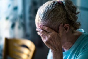 A sad elderly woman feels lonely, grappling with loss or a headache. 