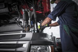 A Caucasian mechanic repairing the engine of a broken semi-truck tractor, focusing on the detailed work involved in truck maintenance and repair.