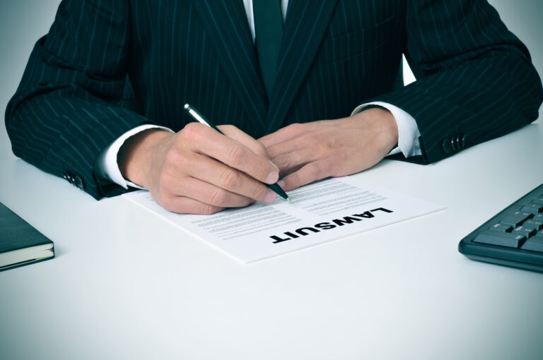 A lawyer reviewing a document labeled "Lawsuit" at his office desk, symbolizing legal action in a personal injury case.