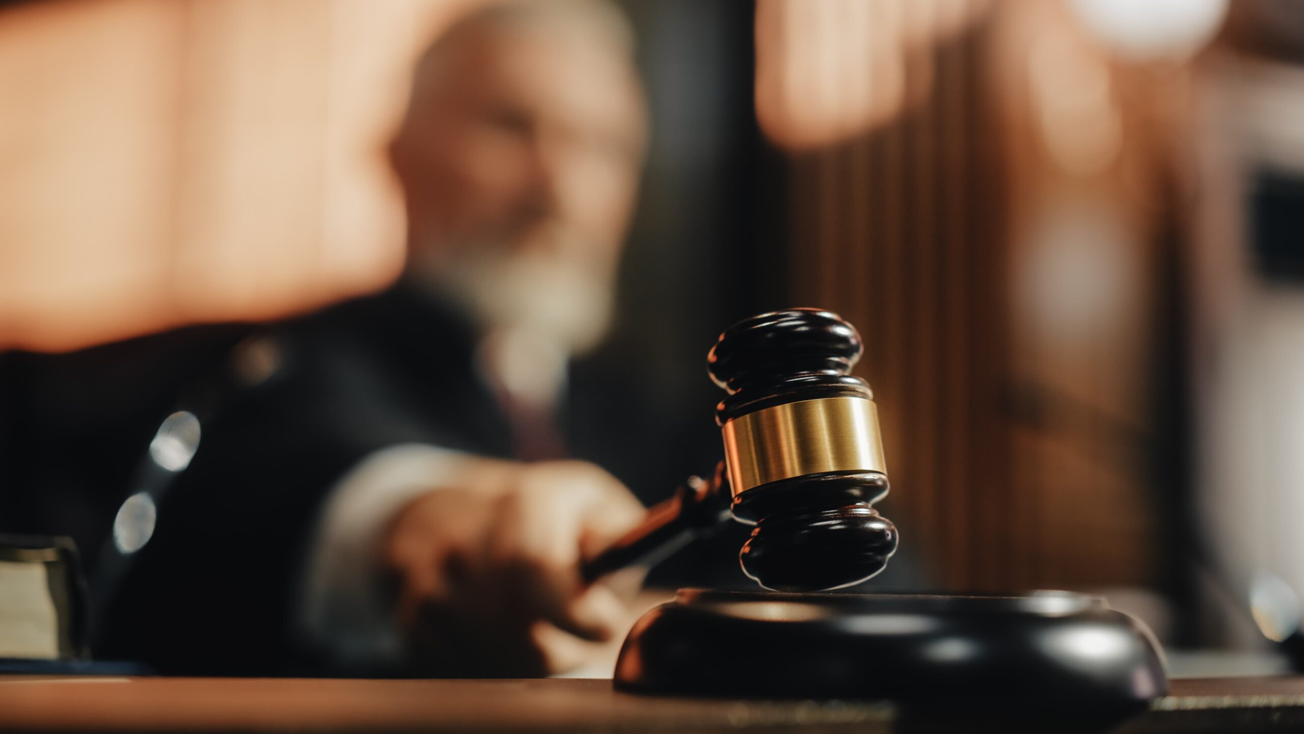 Judge striking gavel in courtroom to deliver legal decision.
