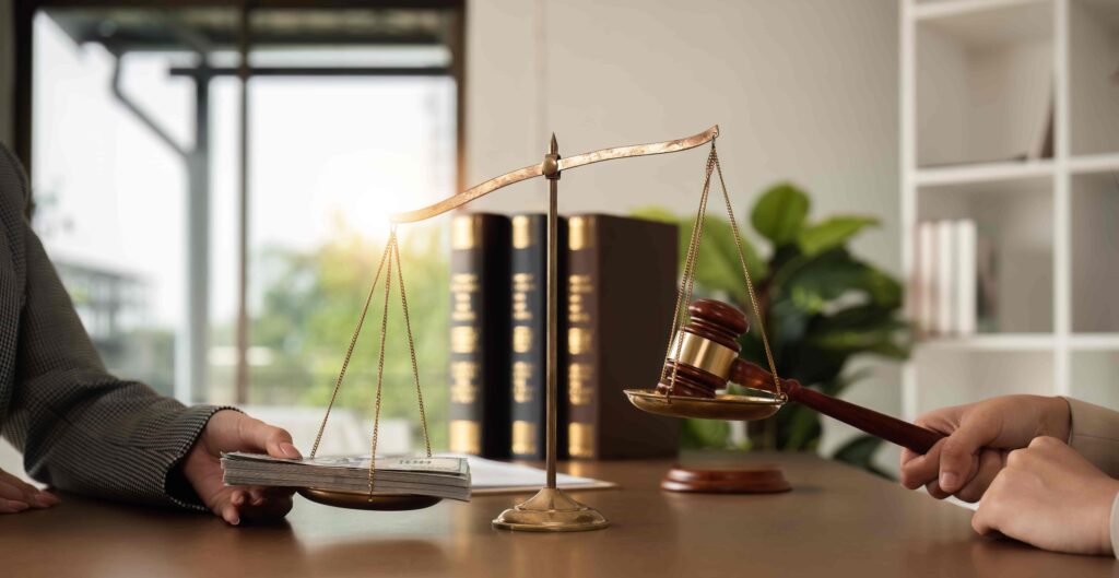 Scales of justice with gavel and money symbolizing legal settlement, bribery, or financial compensation in a law office