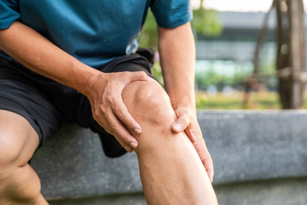 Person holding injured knee in pain after accident.
