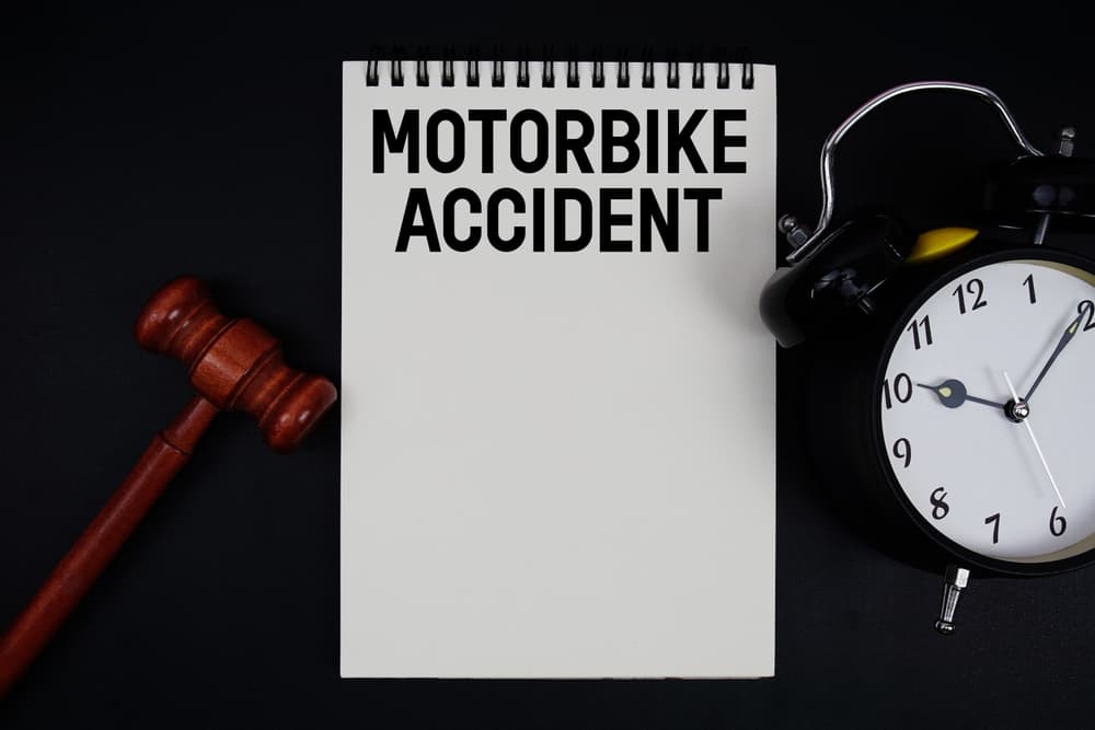 Motorbike accident lawsuit timeline concept with gavel, clock, and notebook illustrating the duration and legal process after a motorcycle crash.